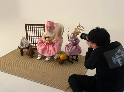 바닥에 앉아 아기 눈높이에서 한복 입은 돌 아기를 촬영 중인 이성현 작가