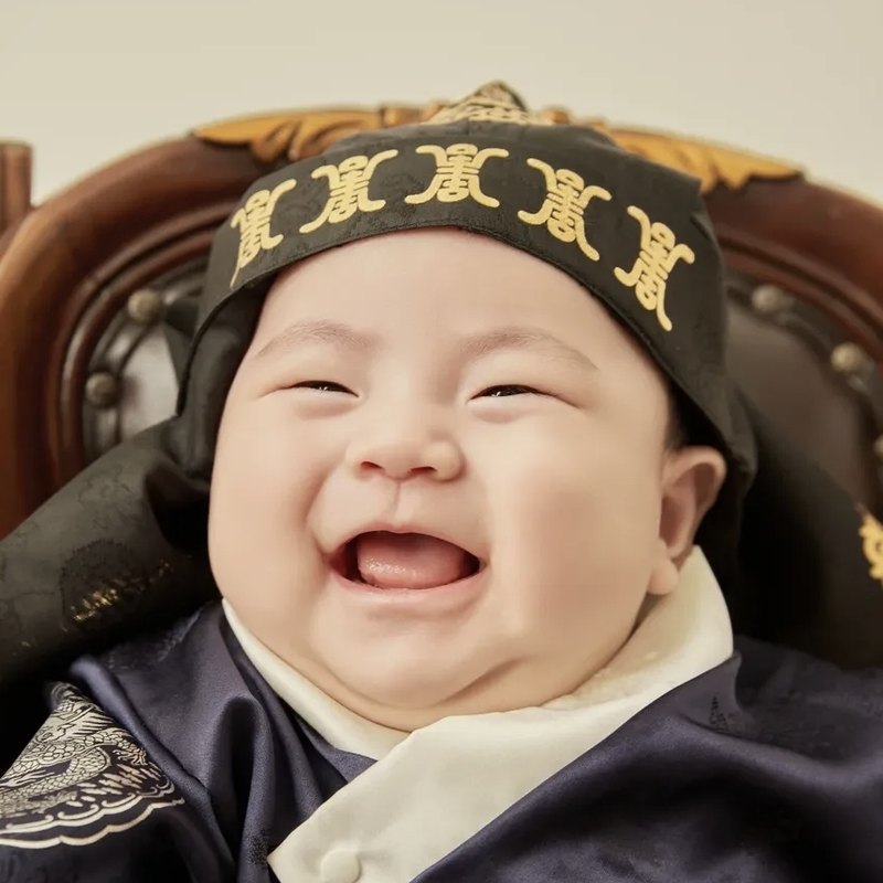 남색 한복에 호건을 쓰고 함박웃음을 짓는 돌 아기