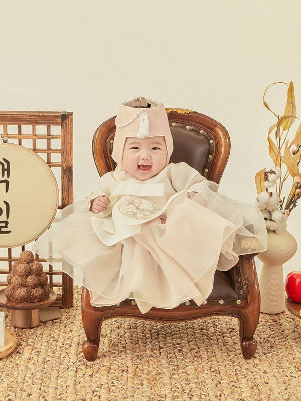아이보리 한복 드레스와 굴레를 쓴 아기가 방긋 웃는 백일 한복 백일사진
