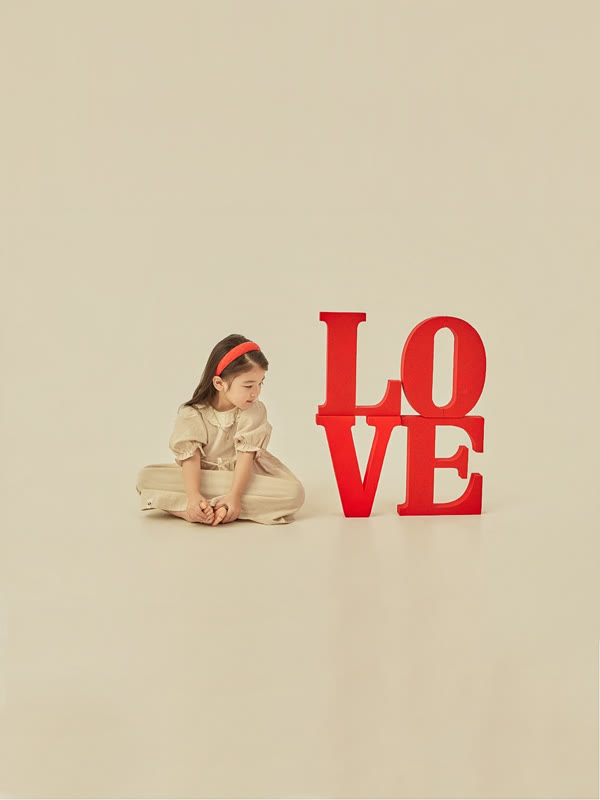 빨간 머리띠를 한 여자아이가 LOVE 글자 소품 옆에 다소곳이 앉은 어린이 프로필 사진